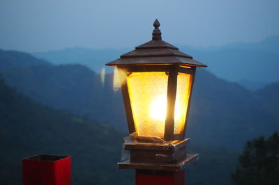 Close-up of illuminated lamp against sky at desk