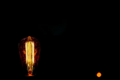 Close-up of illuminated light bulb against black background