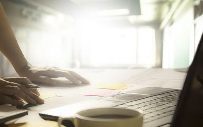 Cropped hands of businessman using laptop on table in office