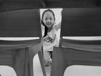 Portrait of girl seen through wooden chairs on floor