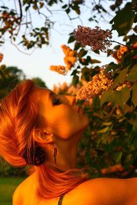 Close-up of young woman smelling flowers during sunset