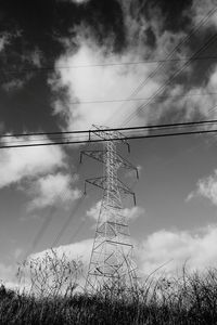 Low angle view of electricity pylon against cloudy sky