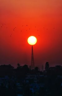 Silhouette buildings against orange sky during sunset