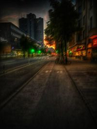 Illuminated road amidst buildings in city at night