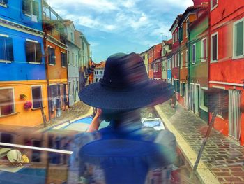 Rear view of woman on train in city against sky