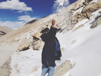 Woman throwing powder snow against sky