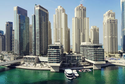 Modern buildings by harbor against sky in city