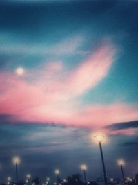 Low angle view of illuminated street light against cloudy sky