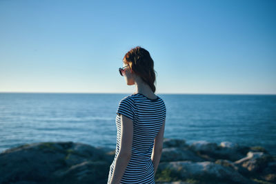 Young woman looking at sea against clear sky