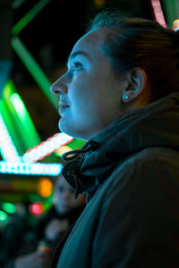 Side view of young woman in city at night