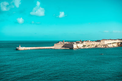 Scenic view of sea by buildings against sky