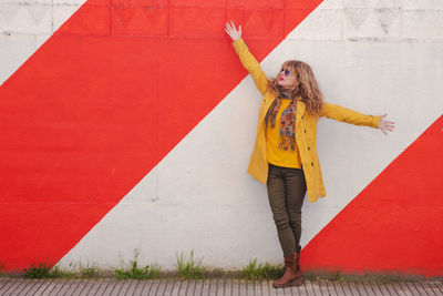 Woman with open arms on the street outdoors with striped wall