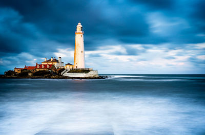 Lighthouse by sea against sky