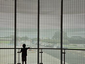 Silhouette rear view of boy looking through window