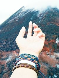 Cropped hand of person against mountain