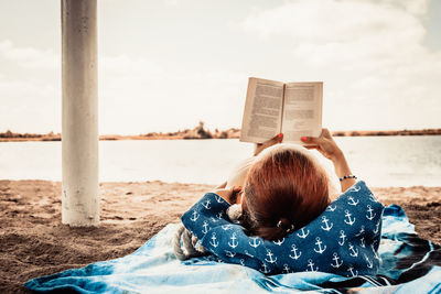 Rear view of woman lying on beach