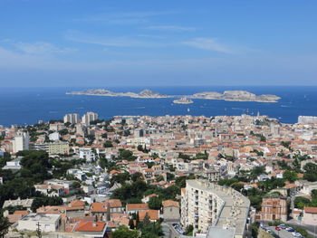 Aerial view of townscape by sea against sky