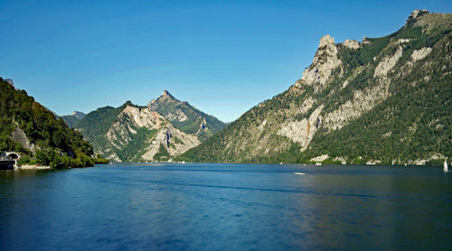 Scenic view of lake and mountains against clear blue sky