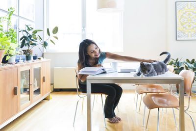 Woman petting cat while working at home office