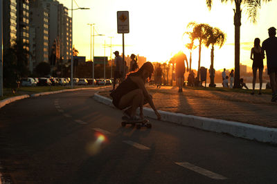 Young woman skateboarding on street during sunset