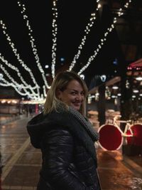 Side view portrait of smiling woman standing at night during christmas