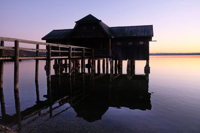 Reflection of house in sea against sky during sunset