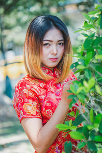 Portrait of beautiful woman standing against plants