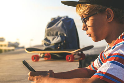 Teen using smartphone app leaning on concrete wall outdoor. young boy play video online on cellphone