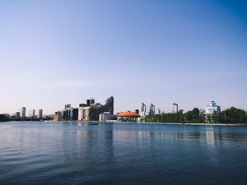 Buildings by river against clear sky