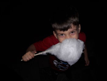 Portrait of boy holding camera over black background