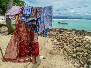 Clothes drying on beach by sea against sky