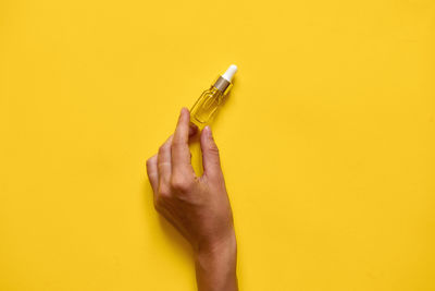 Close-up of woman hand on yellow background