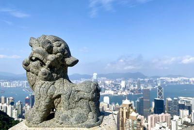 Statue of buildings in city against sky