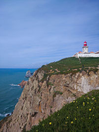 Lighthouse amidst sea and buildings against sky