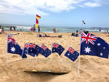 Scenic view of flags on beach against sky