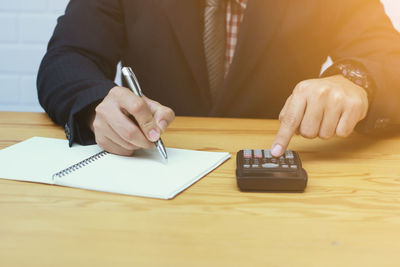 Midsection of man holding paper while sitting on table