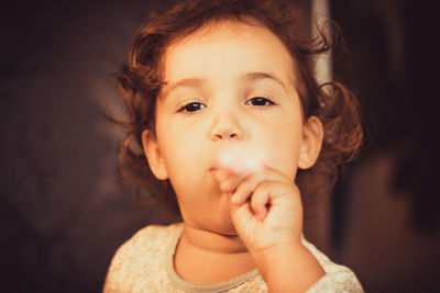 Cute little girl blowing party horn blower and looking at camera.