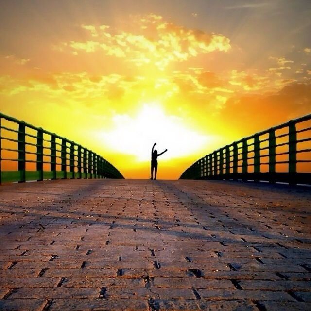 sunset, the way forward, sky, orange color, railing, cloud - sky, diminishing perspective, silhouette, full length, vanishing point, built structure, walking, transportation, sunlight, cloud, outdoors, lifestyles, nature