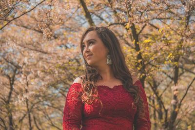 Beautiful woman standing against trees during autumn