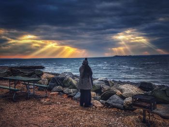Rear view of woman looking at sea during sunset 