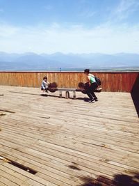 Mother with son enjoying seesaw against sky on sunny day