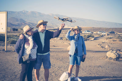 Friends flying drone while standing at desert