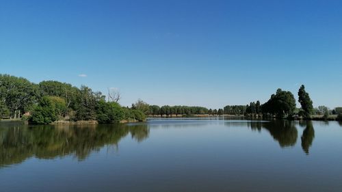 Scenic view of lake against clear blue sky
