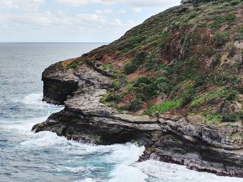 Scenic view of sea by cliff against sky