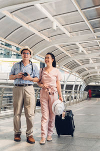 Smiling couple walking on bridge in city