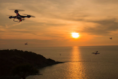 Silhouette of jumping over sea against sky during sunset