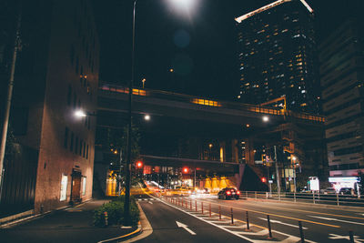 Road passing through illuminated city at night