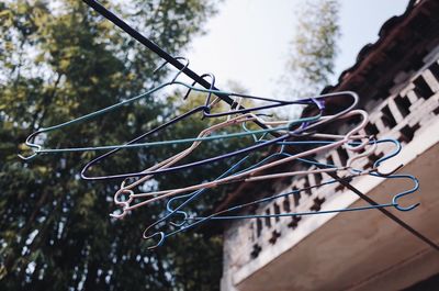 Low angle view of clothespins hanging on rope against trees