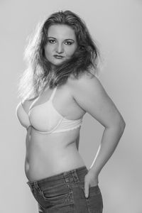 Portrait of young woman standing against white background