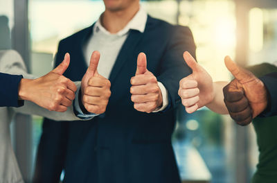 Midsection of businessman gesturing thumbs up